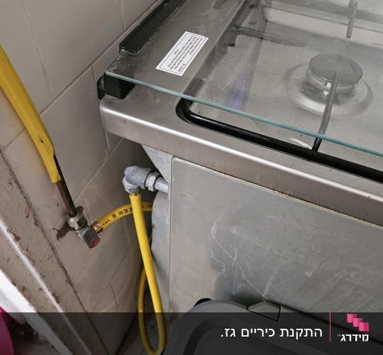 תנור גז עם צינור גז צהוב וחיבור לקיר